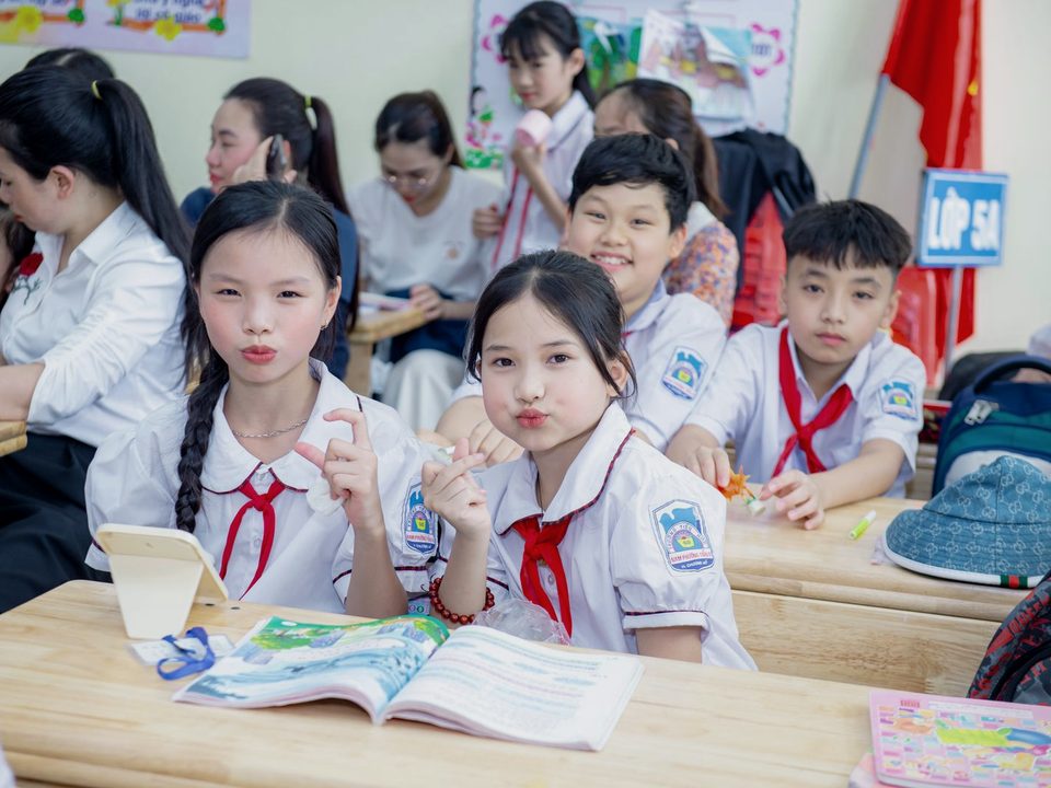 Lớp học: các em học sinh đeo khăn quàng đỏ chăm chú học bài