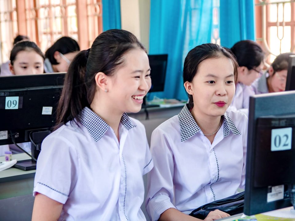 Hai nữ sinh vui vẻ học kỹ năng tin học trong phòng máy